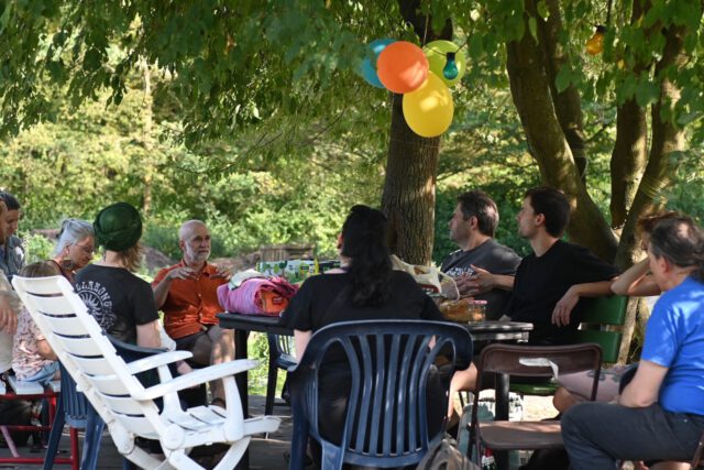 Mitglieder der Die PARTEI-Klima-Fraktion sitzen an einem Tisch und hören Erklärungen zur Solidarischen Landwirtschaft zu.