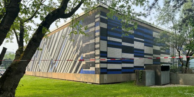 Das Bild zeigt die mit farbigen Kacheln künstlerisch gestaltete Fassade eines Gebäudes. Die Fassade wurde von Günter Fruhtrunk gestaltet.